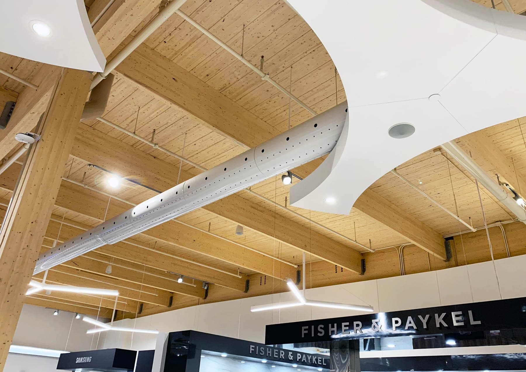 Exposed air diffusers running along a timber ceiling in a retail store
