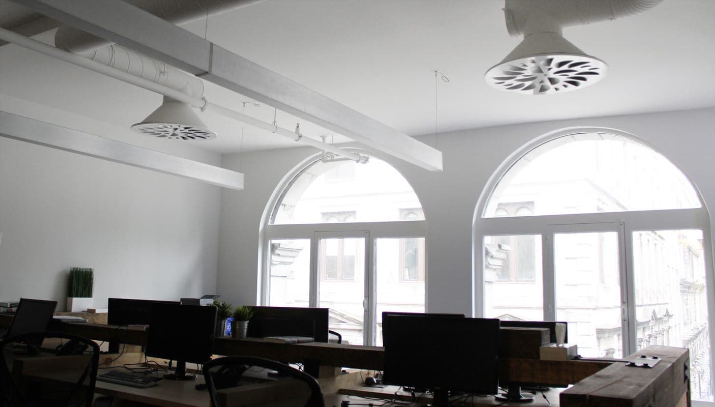 Exposed ductwork and diffusers in a room with arched windows
